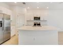 Well-lit kitchen features stainless steel appliances, white cabinets, and center island at 3067 Novara Ln, Lakewood Ranch, FL 34211
