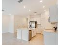 Bright kitchen features a stainless steel refrigerator, island with sink, and ample counter space at 3067 Novara Ln, Lakewood Ranch, FL 34211