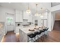 Bright, white kitchen with a marble island, pendant lighting, stainless steel appliances, and hardwood flooring at 1783 Bayview Dr, Sarasota, FL 34239