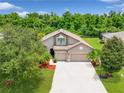Aerial view shows a beautiful home with a large driveway, well-maintained lawn, and lush trees surrounding the property at 5919 Lexington Dr, Parrish, FL 34219