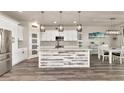Bright kitchen with modern appliances, a stylish island with a white and gray wood accent, pendant lighting, and a spacious pantry at 2352 Marton Oak Blvd, North Port, FL 34289