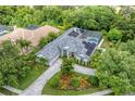 An aerial view showcasing a beautiful home with a pool, solar panels, and mature trees at 6935 Cumberland Ter, University Park, FL 34201