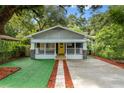 Lovely home with awnings, a yellow front door, and lush, mature landscaping at 807 E Genesee St, Tampa, FL 33603