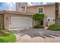 Front view of a tan townhome featuring a white garage door and brick driveway at 1711 Starling Dr # 1711, Sarasota, FL 34231