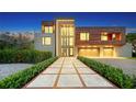Modern home with brick and wood exterior, double garage, and landscaped walkway at night at 2945 Pyrula Dr, Longboat Key, FL 34228
