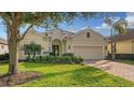 Tan single-story home with brick driveway and landscaping at 7275 Lismore Ct, Lakewood Ranch, FL 34202