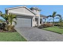 Two-story house with gray garage door, paver driveway, and tropical landscaping at 17931 Palmiste Dr, Bradenton, FL 34202
