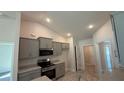 Well-lit kitchen with stainless steel appliances, granite counters, gray cabinetry, and wood-look tile flooring at 3884 S Haberland Blvd, North Port, FL 34288