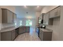 Spacious kitchen boasting stainless steel appliances, gray cabinetry, granite countertops, and wood-look tile flooring at 3884 S Haberland Blvd, North Port, FL 34288
