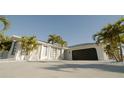 Modern home exterior with white walls, dark garage door, and palm trees at 18770 Mcgrath Cir, Port Charlotte, FL 33948