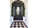 Inviting front door entry with black door and stylish planters at 11061 Sandrift Ave, Englewood, FL 34224