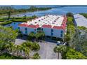 Aerial view of condo building with red tile roof, and lush landscaping at 3705 E Bay Dr # 115, Holmes Beach, FL 34217