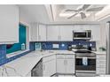 Modern kitchen with white cabinets, blue tile backsplash, and stainless steel appliances at 3705 E Bay Dr # 115, Holmes Beach, FL 34217