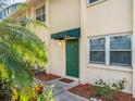 Condo building entry with green door and tropical landscaping at 4800 Rilma Ave # 143, Sarasota, FL 34234