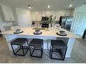 Modern kitchen island with quartz countertops, bar seating, stainless appliances, and bright cabinetry at 17445 Opal Sand Dr # 104, Venice, FL 34293