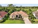 Inviting single-story home featuring a tile roof, lush landscaping, and views of a golf course in the distance at 13791 Palmetto Point Ct, Port Charlotte, FL 33953