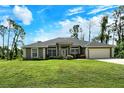 Single story home with a gray exterior and lush lawn at 2474 Kabbaby St, North Port, FL 34288