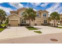 Tan three-story townhome with two-car garage, palm trees, and manicured landscaping at 8269 Enclave Way # 103, Sarasota, FL 34243