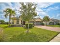 House exterior showcasing a three-car garage, lush lawn, and palm trees at 5514 69Th E Pl, Ellenton, FL 34222