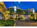 Luxury condo building at night with palm trees and a paved driveway at 2251 Gulf Of Mexico Dr # 301, Longboat Key, FL 34228