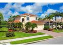 Beautiful two-story home featuring a well-manicured lawn, tropical landscaping, and terracotta tile roof at 11492 Dancing River Dr, Venice, FL 34292
