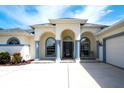 Elegant home showcasing a covered front entrance with stately columns, arched windows, and double rocking chairs at 15923 29Th E St, Parrish, FL 34219