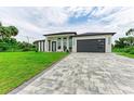 Modern house with a gray garage door and green lawn at 13457 Drysdale Ave, Port Charlotte, FL 33981