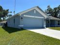 Side view of a one-story home with an attached two-car garage and a well-maintained lawn at 4865 Manila Ave, North Port, FL 34288