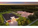 Stunning aerial view of a home with lake frontage, a manicured lawn, and mature trees at 16211 Mulholland Rd, Parrish, FL 34219