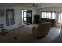Cozy living room with neutral carpet, ceiling fan, and access to the sunroom for relaxed living at 6064 Shearwater Dr, Englewood, FL 34224