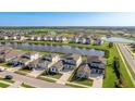 An aerial view of a neighborhood highlighting homes surrounding a picturesque pond with a sprawling green landscape beyond at 9478 Tequila Sunrise Dr, Sarasota, FL 34241