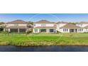 A view of the backyard featuring manicured grass, a covered patio, and views of the pond beyond at 9478 Tequila Sunrise Dr, Sarasota, FL 34241