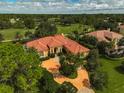 Expansive aerial view of a home near a golf course with a red tile roof and circular driveway at 909 Macewen Dr, Osprey, FL 34229