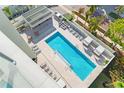 Aerial view of a modern condo building's pool with lounge seating and manicured landscaping at 111 Golden Gate Pt # 201, Sarasota, FL 34236