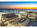 Relaxing rooftop patio with comfortable seating, a modern fire pit, and stunning views of the bridge and twilight sky at 111 Golden Gate Pt # 201, Sarasota, FL 34236