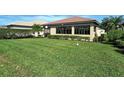 Large grassy backyard with a partially visible pool and screen enclosure at 1130 Cielo Ct, North Venice, FL 34275