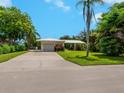 Beautiful one-story home with lush landscaping, mature trees, and a spacious driveway at 302 Mendez Dr, Sarasota, FL 34243