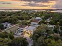 Aerial view showcasing a modern home in a lush neighborhood near the water at sunset at 3464 Camino Real, Sarasota, FL 34239