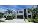Contemporary home with a black garage door, a simple design, and fresh landscaping at 3464 Camino Real, Sarasota, FL 34239