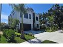 Striking modern home with a black garage door and lush landscaping, set against a blue sky at 3464 Camino Real, Sarasota, FL 34239