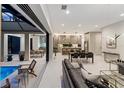 Open-concept living space with modern furnishings, a dining area, and a seamless transition to outdoor pool at 3464 Camino Real, Sarasota, FL 34239