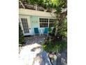 Charming front patio featuring teal chairs, a small table, and lush greenery at 1603 Gulf N Dr # 5, Bradenton Beach, FL 34217