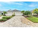 Two-car garage, paver driveway, and landscaped yard with palm trees at 2942 Trustee Ave, Sarasota, FL 34243