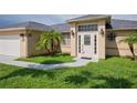 Front view of a tan house with a white door, palm trees and a walkway at 13592 Clara Ln, Port Charlotte, FL 33981