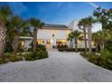 An eye-level exterior view of a modern-designed home, surrounded by palm trees and lush greenery at 7665 Sanderling Rd, Sarasota, FL 34242