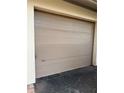 Closed, light brown garage door in a home's facade, providing secure and private parking at 3601 Quail Hollow Ln, Bradenton, FL 34210