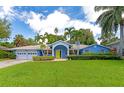 Charming one-story blue home featuring well-manicured lawn, tropical landscaping and a bright yellow front door at 1389 Harbor Dr, Sarasota, FL 34239