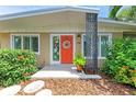 Inviting front entrance with a bright orange door, decorative wreath, and colorful stained-glass window at 136 Crescent Dr, Anna Maria, FL 34216