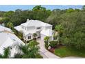 Gorgeous home with a white roof, lush landscaping, and a private driveway nestled in a golf community at 7620 Club Ln, Sarasota, FL 34238
