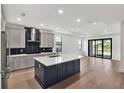 Spacious kitchen with stainless steel appliances, center island, hardwood floors, and a seamless flow to the living area at 18773 Dayspring Pl, Venice, FL 34293